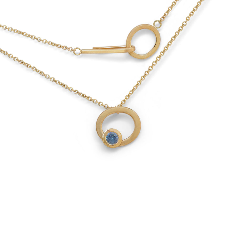 Gold asymmetrical halo pendant with blue sapphire